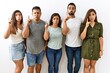 © Krakenimages.com - Group of young hispanic friends standing together over isolated background pointing up looking sad and upset, indicating direction with fingers, unhappy and depressed.