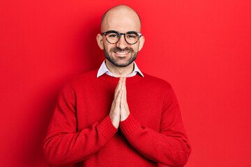 Sticker - Young bald man wearing casual clothes and glasses praying with hands together asking for forgiveness smiling confident.