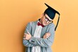 © Krakenimages.com - Young caucasian nerd man wearing glasses and graduation cap hugging oneself happy and positive, smiling confident. self love and self care