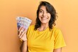 © Krakenimages.com - Young hispanic woman holding 20 polish zloty banknotes looking positive and happy standing and smiling with a confident smile showing teeth