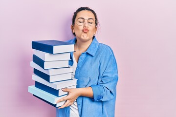 Poster - Young hispanic woman wearing glasses and holding books looking at the camera blowing a kiss being lovely and sexy. love expression.