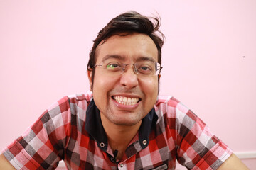 Canvas Print - Smiling Indian man in checkered clothes and eyewear isolated on a pink background