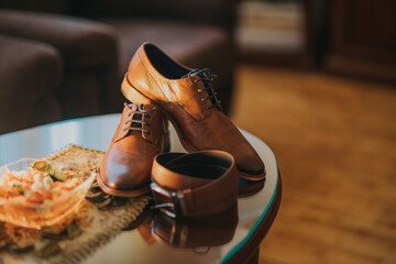 Poster - Closeup shot of a pair of brown leather shoes and a belt on a table