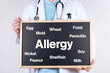 Doctor with a board with the word allergy and some foods that cause allergies