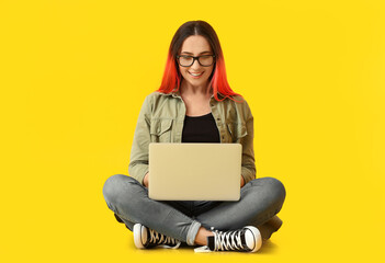 Female programmer using laptop on color background