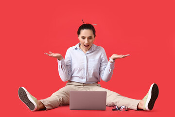 Wall Mural - Surprised female programmer using laptop on color background