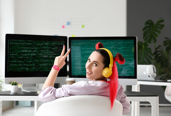 female programmer showing victory gesture in office