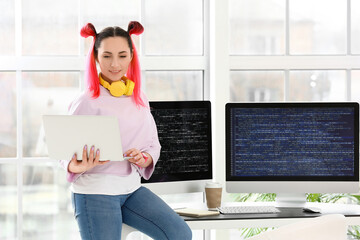 Wall Mural - Female programmer working with laptop in office