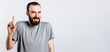© Daria Lukoiko - Portrait of cheerful young handsome man smiling looking at camera pointing finger upwards on white background with space for advertising mock up