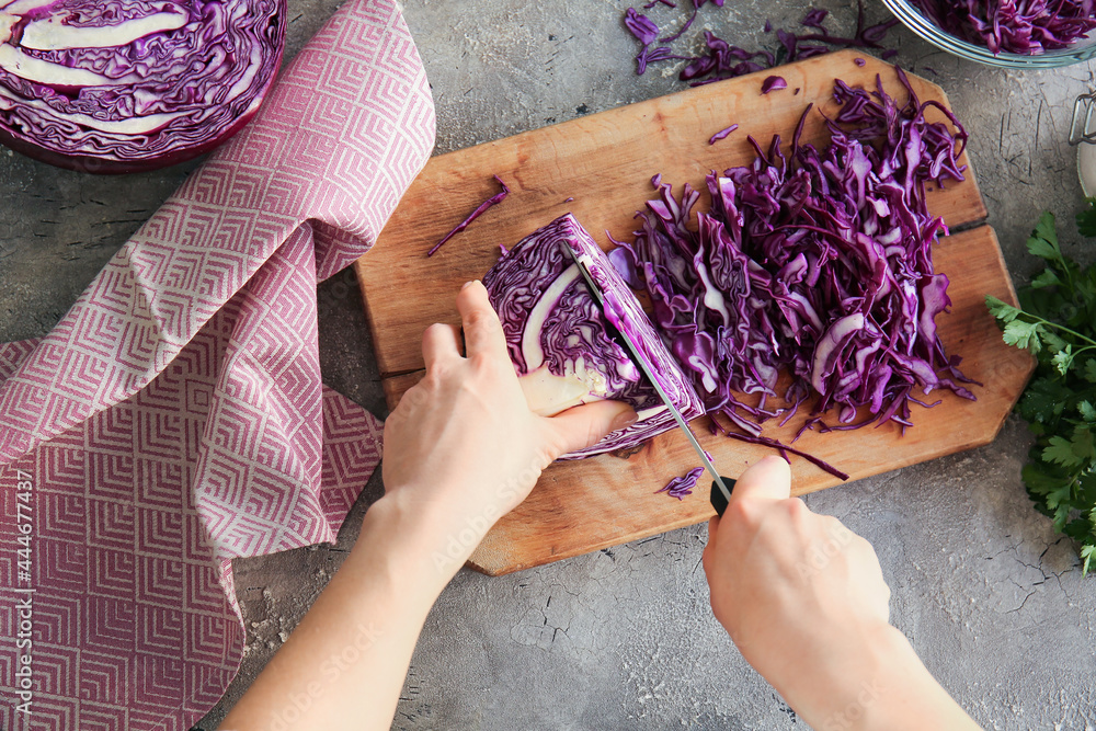 Woman cutting fresh purple cabbage on table