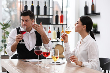 Sommeliers tasting different sorts of wine at table indoors