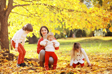 Young family on a walk in the autumn park on a sunny day. Happiness to be together.