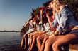 © Zoran Zeremski - Group of friends sitting on the edge of a pier having fun and enjoying a summer day at the lake.