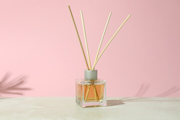 diffuser bottle with sticks against pink background