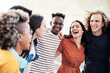 © Davide Angelini - Young happy people laughing together - Multiracial friends group having fun on city street - Diverse culture students portrait celebrating outside - Friendship, community, youth, university concept