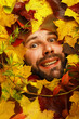 Artistic conceptual autumn beard man portrait. Colorful leaves. Leaves of trees around an emotional face. Autumn is coming.