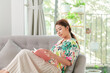 © makistock - Woman reads the book lying on the gray sofa