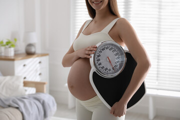 Wall Mural - Young pregnant woman with scales at home, closeup