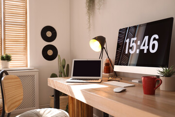 Poster - Modern computer and laptop on wooden desk in room. Interior design