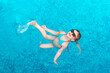 © Елена Гурова - little girl in sunglasses swims in a swimming pool with blue water on a summer day