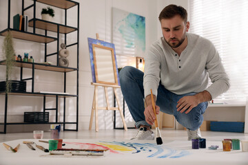 Sticker - Young man painting on canvas with brush in artist studio