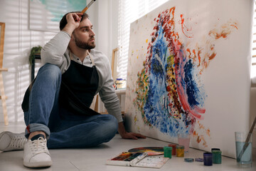 Sticker - Young man painting on canvas with brush in artist studio