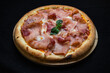 Pizza with tomato sauce, mozzarella and ham on a black background.