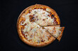 Pizza quatro formaggi with tomato sauce and 4 kinds of cheese on a black background.