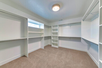 Walk in closet of house with empty built in shelves and two levels clothing rods