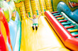 Little boy child rides on an inflatable multi-colored slide.