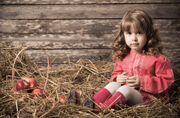 little beautiful girl with apples on old wooden background