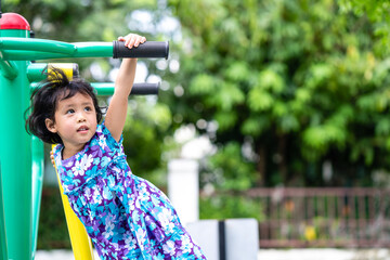 Wall Mural - Active little girl playing at outdoor playground in summer.