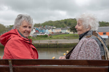 Rear view of two senior woman sitting on a park bench outdoors 