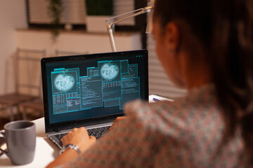 Woman doing cyberspace criminal activity hacking firewall using laptop from home office at night time. Programmer writing a dangerous malware for cyber attacks using performance laptop during midnight
