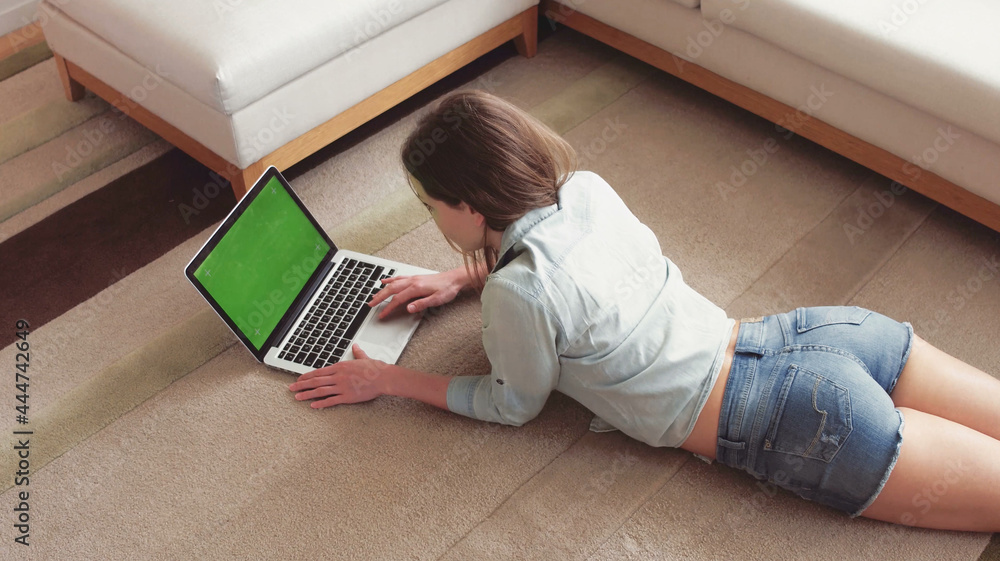 Relaxing at home. Beautiful young woman using her laptop while lying on ...