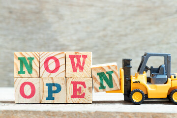 Poster - Toy forklift hold letter block w in word now open on wood background