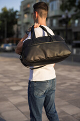 Wall Mural - A man walks around the city holding bag on his shoulder