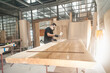 Man in respirator mask painting wooden planks at workshop. Craftsman modern furniture factory paint