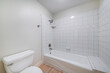 Interior of a bathroom with toilet bowl and alcove bathtub shower combo with tiles