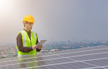 An engineer works on the inspection and maintenance of equipment at roof-mounted solar power plants of condominium buildings, houses with a tabletop in his hand.