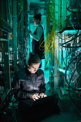 Wall Mural - Vertical portrait of young technician setting up computer network in server room