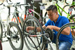 © DragonImages - Serious salesman in uniform adjusting chain of bicycle he is selling in store