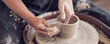 canvas print picture - Close up female hands make dishes from clay. woman hands working on potters wheel. The master potter works in a workshop. banner