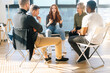 © dikushin - Diverse young colleagues sitting in circle have fun talking on business training with coach by window in light office room. Multiethnic business team discuss ideas engaged in educational meeting.