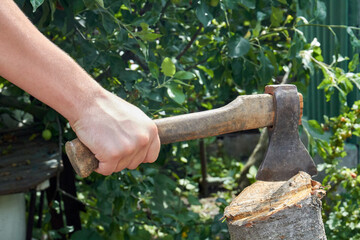 Close-up yog hand with axe cutting a log.