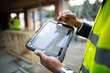 © Paul Bradbury/Caia Image - Male architect looking at blueprints on digital tablet