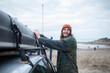 © Sam Edwards/Caia Image - Smiling young man fastening canoe onto car at beach