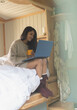 © Sam Edwards/Caia Image - Young woman using laptop in tiny cabin rental bed