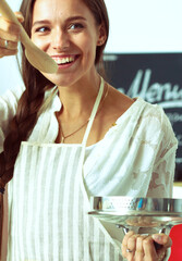 Wall Mural - Cooking woman in kitchen with wooden spoon