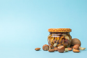 Wall Mural - Nuts and a small jar with honey and nuts on a blue background.